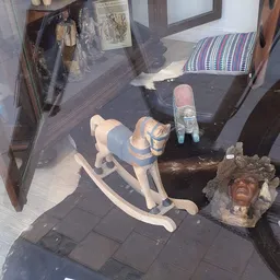 Diverse tweedehands items op de vloer: houten beeldje, sculptuur, schoenen en andere huishoudelijke spullen