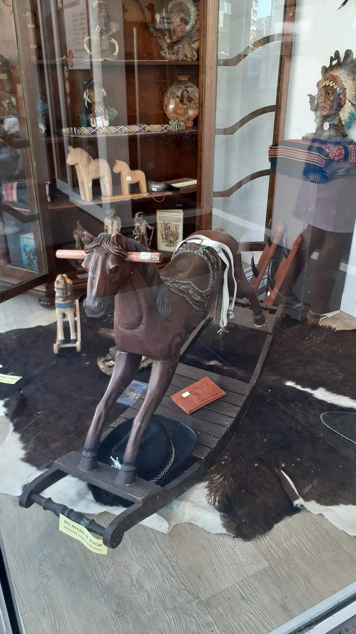 Bruine decoratieve paardenbeeldhouwwerk met zadelwerk en sieraden op zwarte voet in kringloopwinkel
