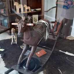 Bruine decoratieve paardenbeeldhouwwerk met zadelwerk en sieraden op zwarte voet in kringloopwinkel