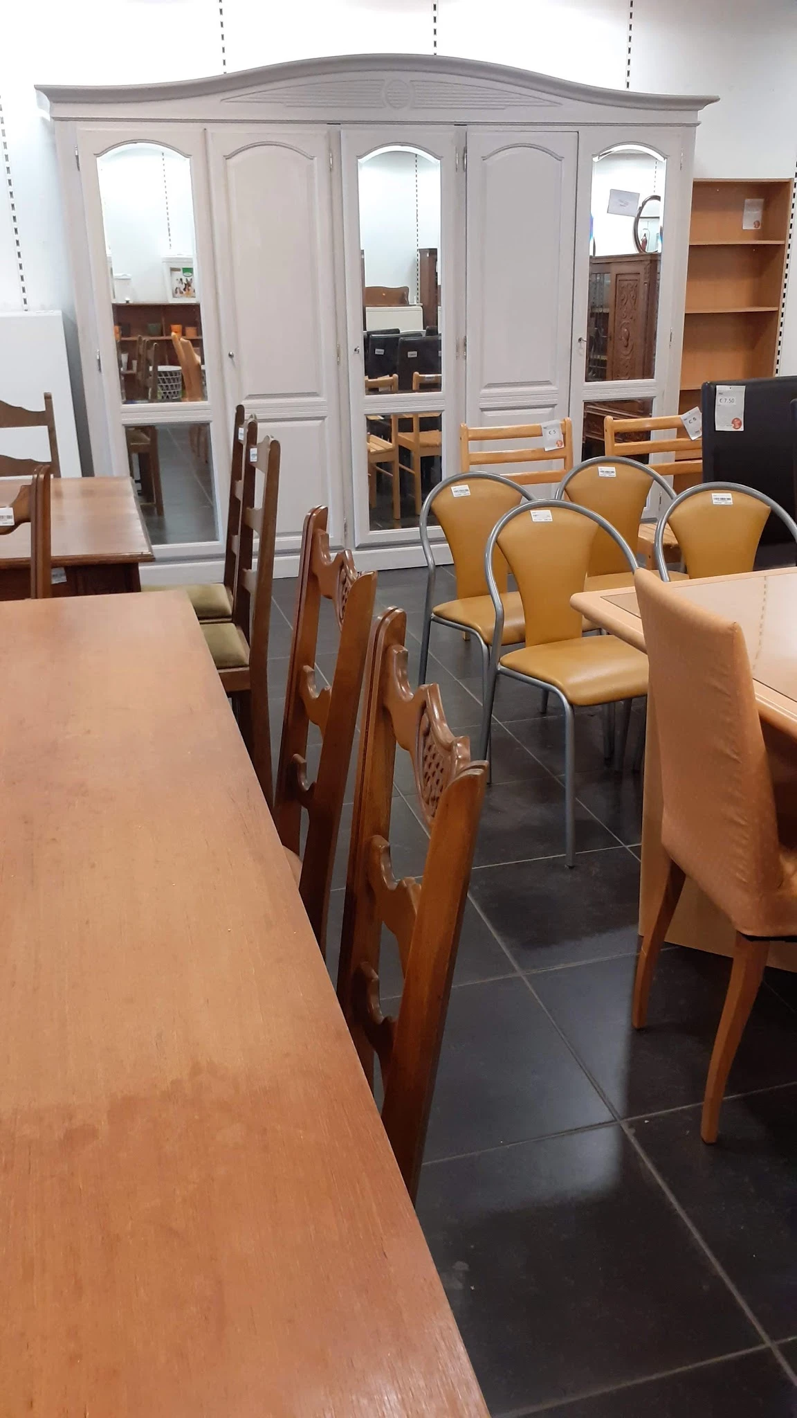 Winkelvloer met diverse stoelen en tafels, voorzijde van de kringloopwinkel