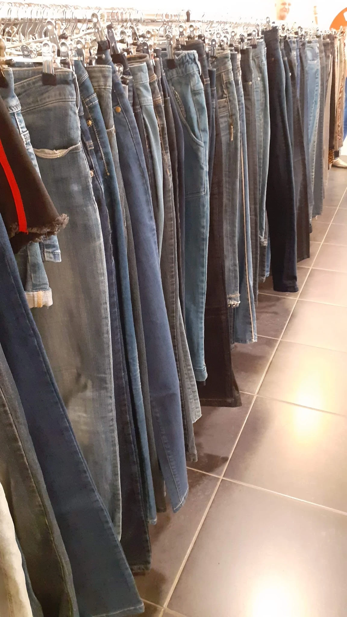 Rekken met tweedehands jeans en broeken in verschillende kleuren en wassingen