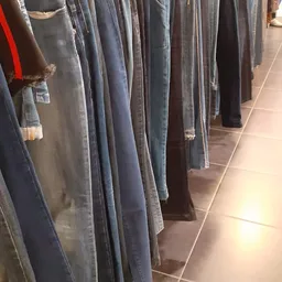 Rekken met tweedehands jeans en broeken in verschillende kleuren en wassingen