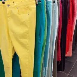 Rekken met gekleurde broeken in verschillende tinten: geel, groen, blauw, grijs, rood en zwart