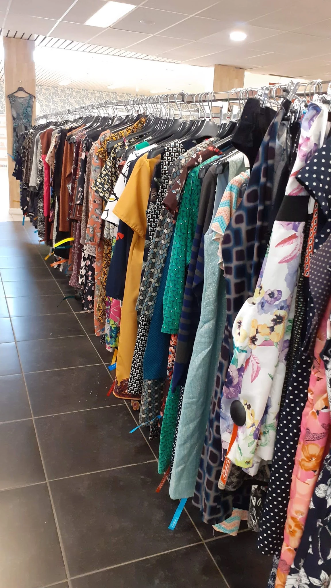 Rekken met tweedehands dameskleding in verschillende kleuren en patronen