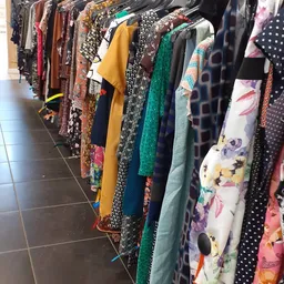 Rekken met tweedehands dameskleding in verschillende kleuren en patronen