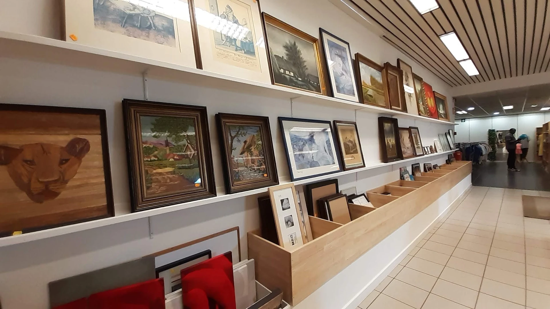 Wandrek met ingelijste schilderijen en kunstprenten, en onderkasten met losse afbeeldingen en framewerk