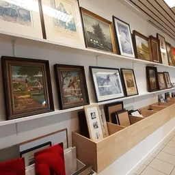 Wandrek met ingelijste schilderijen en kunstprenten, en onderkasten met losse afbeeldingen en framewerk