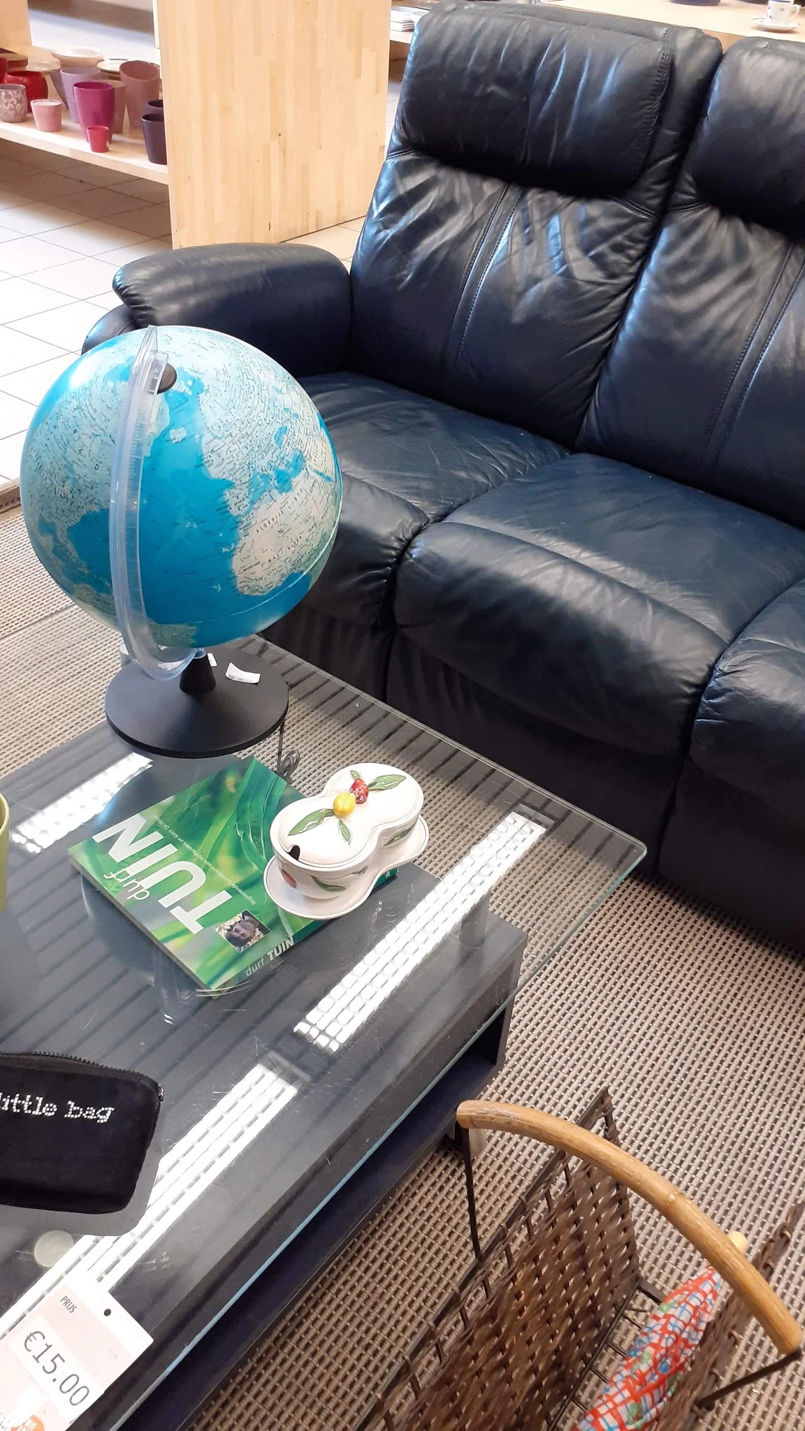 Zwarte leren bank met op tafel een wereldbol, boeken en decoratieve items