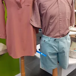 Uitgestalde herenkleding: roze en paarse overhemden en lichtblauwe broeken op mannequins