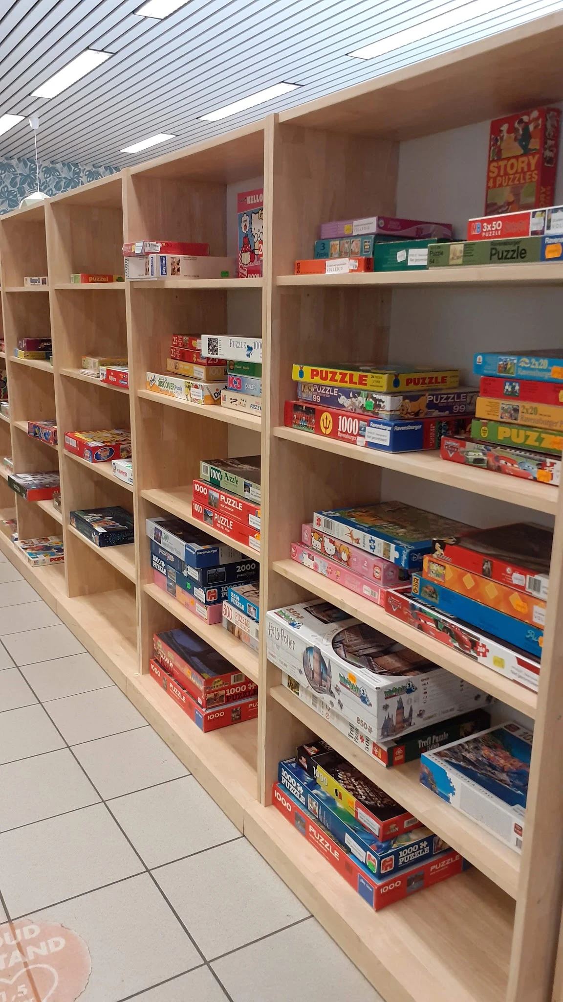 Houten stellingen met gestapelde puzzelboxen en bordspellen in verschillende kleuren