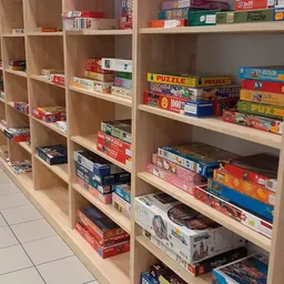 Houten stellingen met gestapelde puzzelboxen en bordspellen in verschillende kleuren