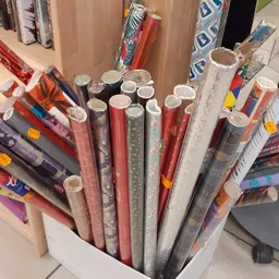 Uitgestalde rollen decoratief papier en behang in verschillende kleuren en patronen