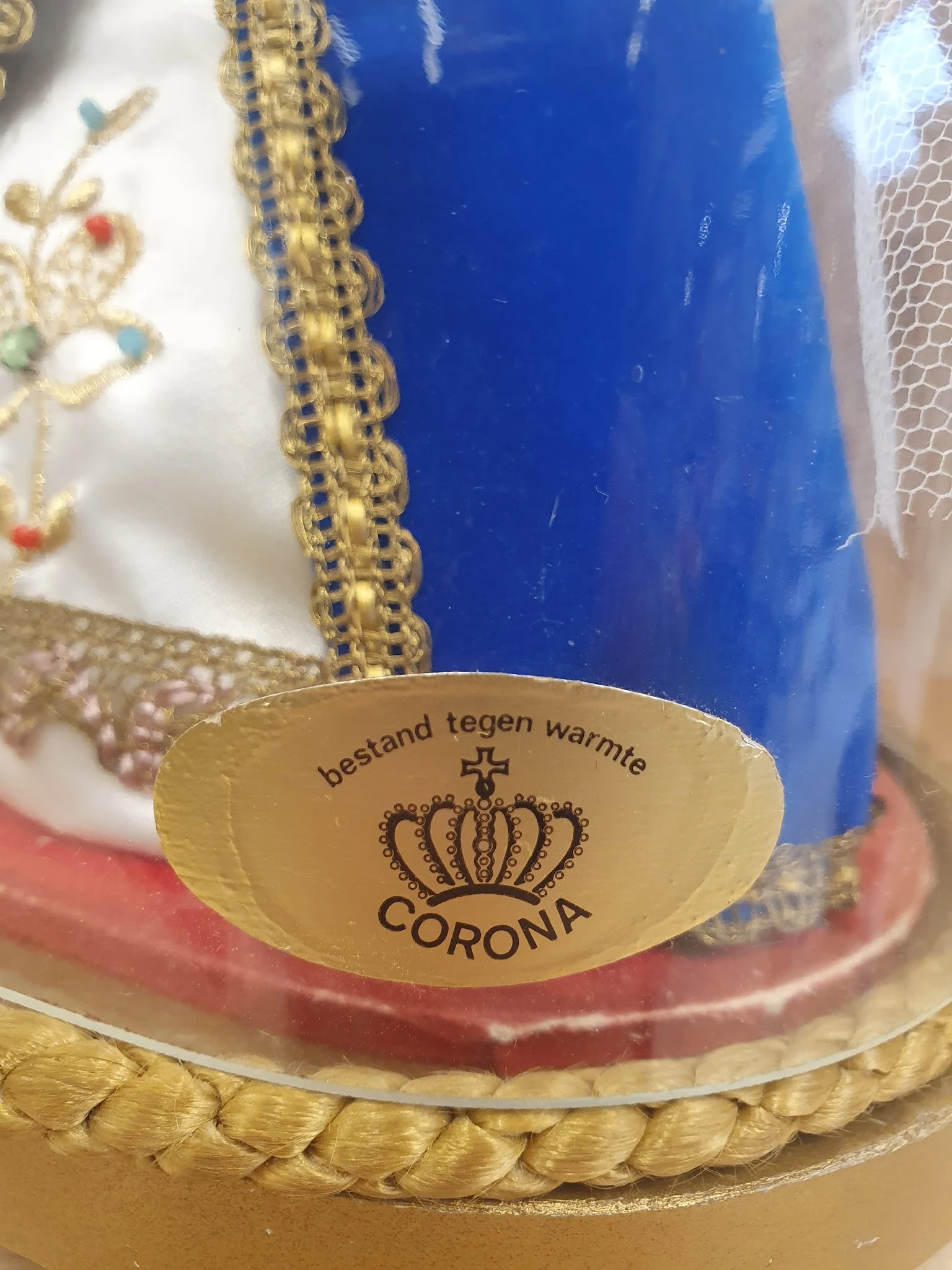 Close-up van een gele decoratieve schaal met 'Corona' opdruk en tekst 'Bestand tegen warmte'