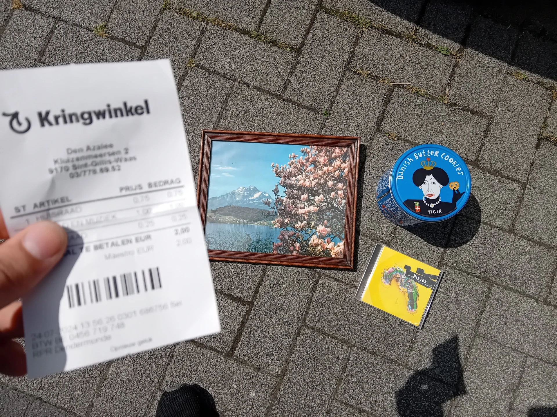 Kassabon, foto in houten lijst, blauw pin-spel en geel artikel op stenen ondergrond