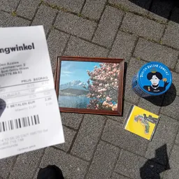 Kassabon, foto in houten lijst, blauw pin-spel en geel artikel op stenen ondergrond