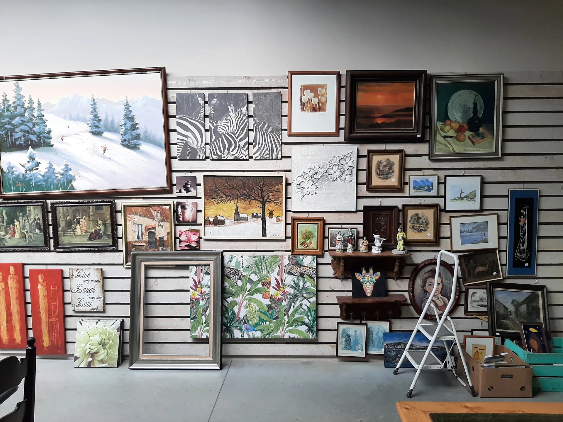Slatwall met uitgestalde kunstwerken, lijsten, prints en decoratieve artikelen in verschillende formaten en stijlen