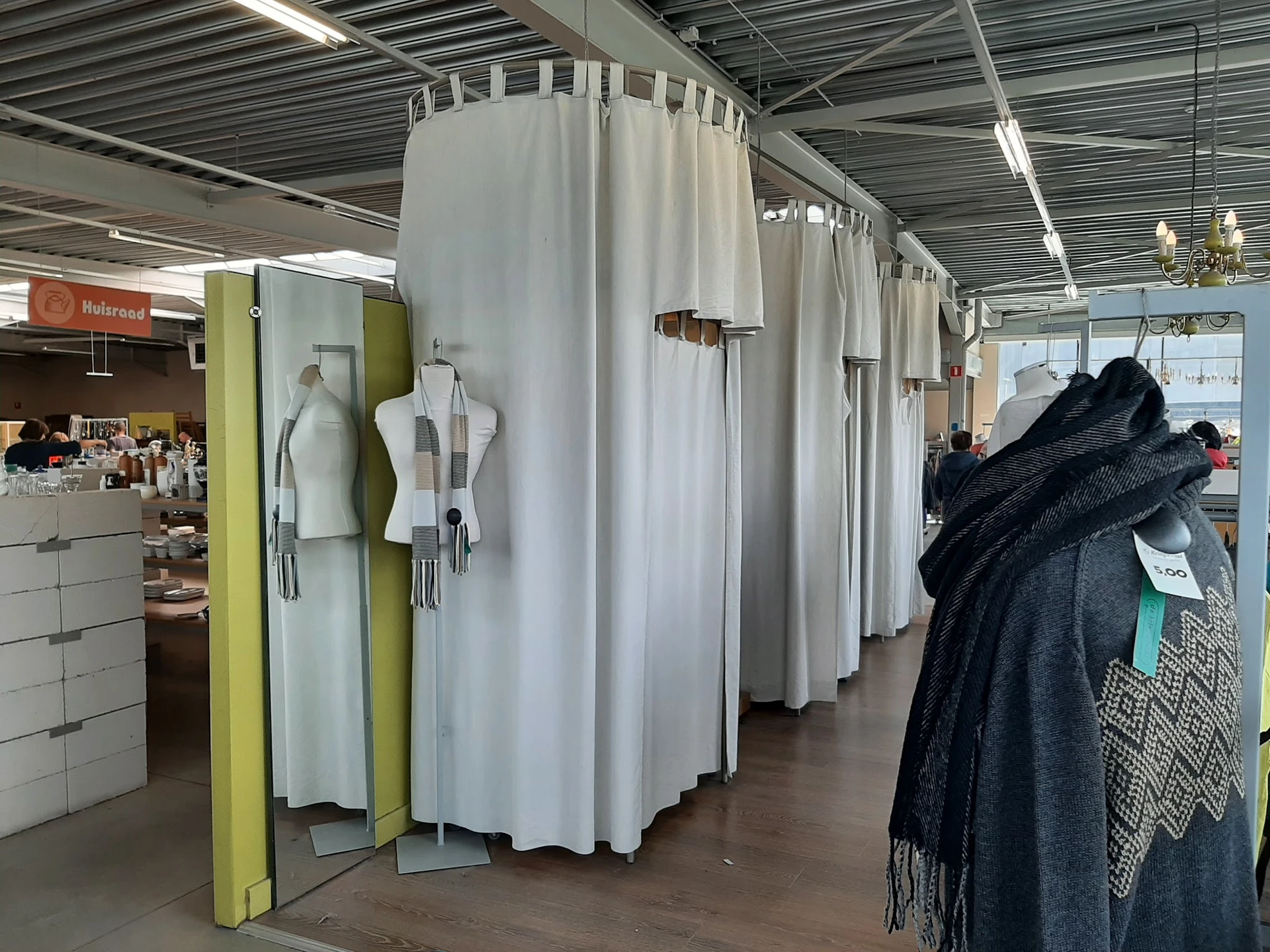 Uitgestalde tweedehands kleding op mannequins en aan rekken in een kringloopwinkel