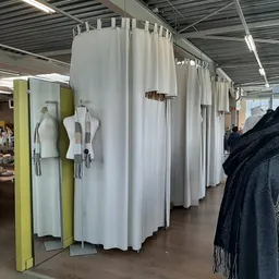 Uitgestalde tweedehands kleding op mannequins en aan rekken in een kringloopwinkel
