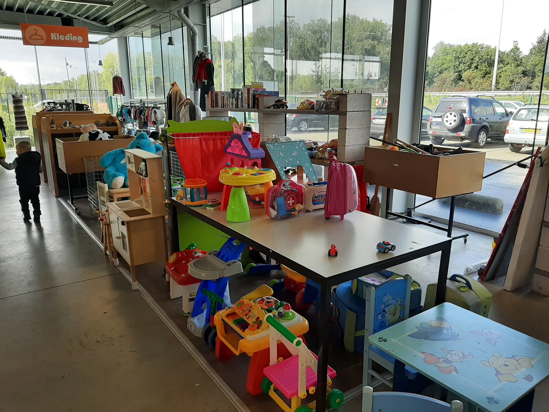 Winkelvloer met kinderartikelen, speelgoed en kleding uitgestald op tafels en in dozen