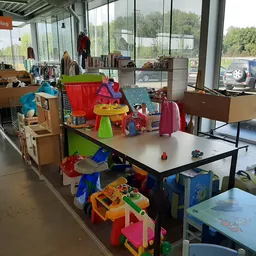 Winkelvloer met kinderartikelen, speelgoed en kleding uitgestald op tafels en in dozen