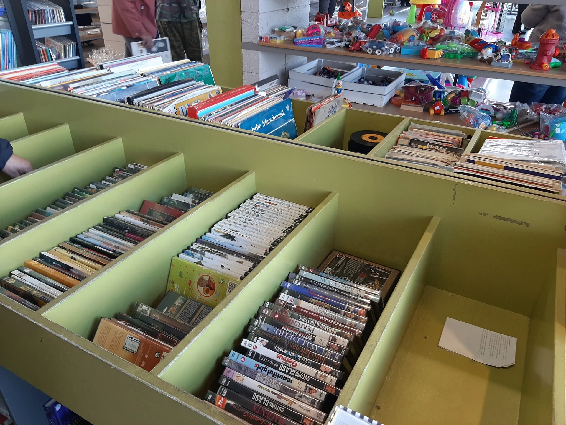 Groene bakken met DVD's en cd's netjes uitgestald in kringloopwinkel