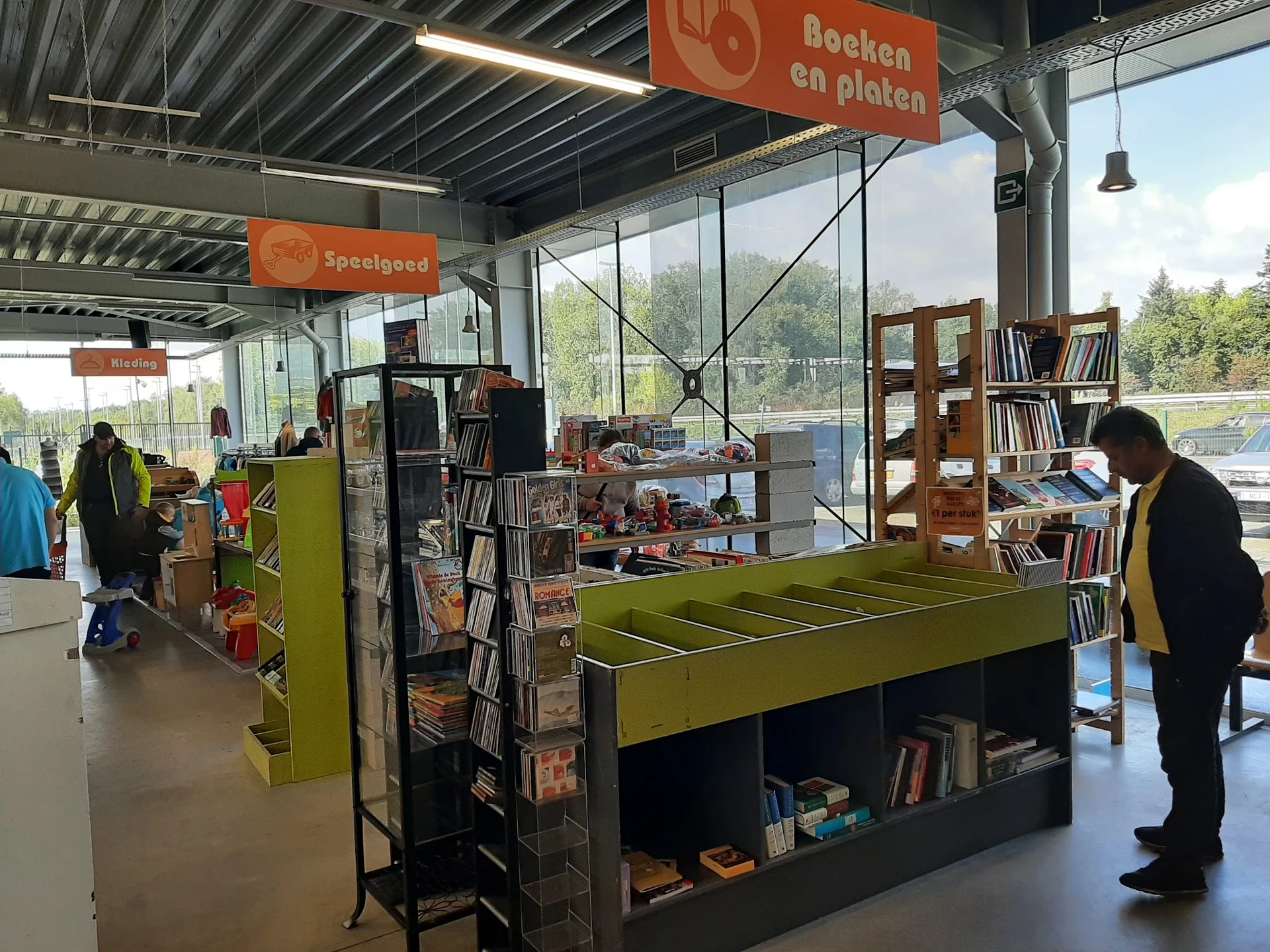 Interieur van kringloopwinkel met groene ping-pongtafel, boekenrekken en bezoekers