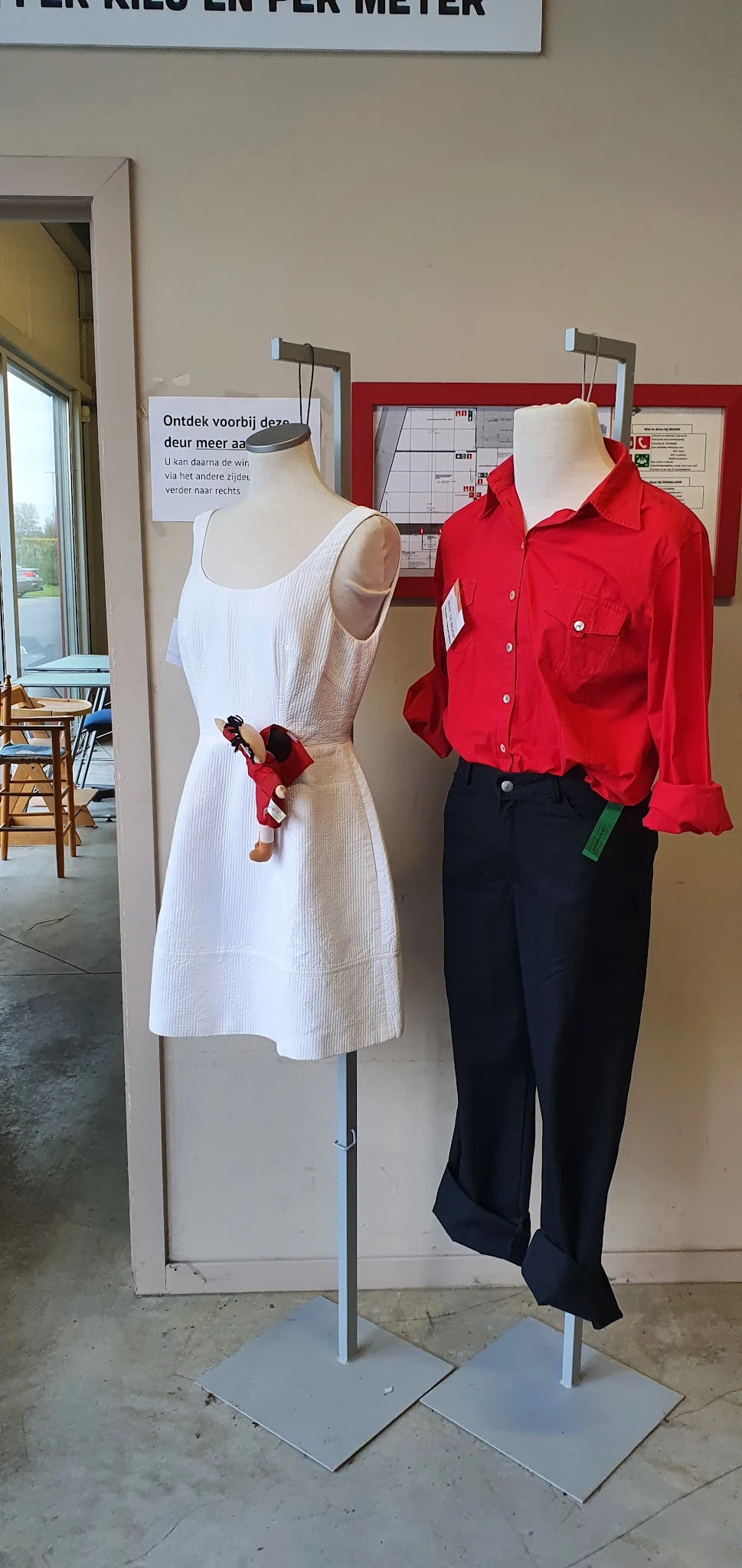 Kledingmanequins met uitgestalde dameskleding: witte jurk en rode blouse met zwarte broek