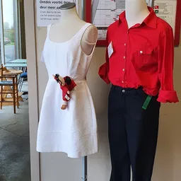 Kledingmanequins met uitgestalde dameskleding: witte jurk en rode blouse met zwarte broek
