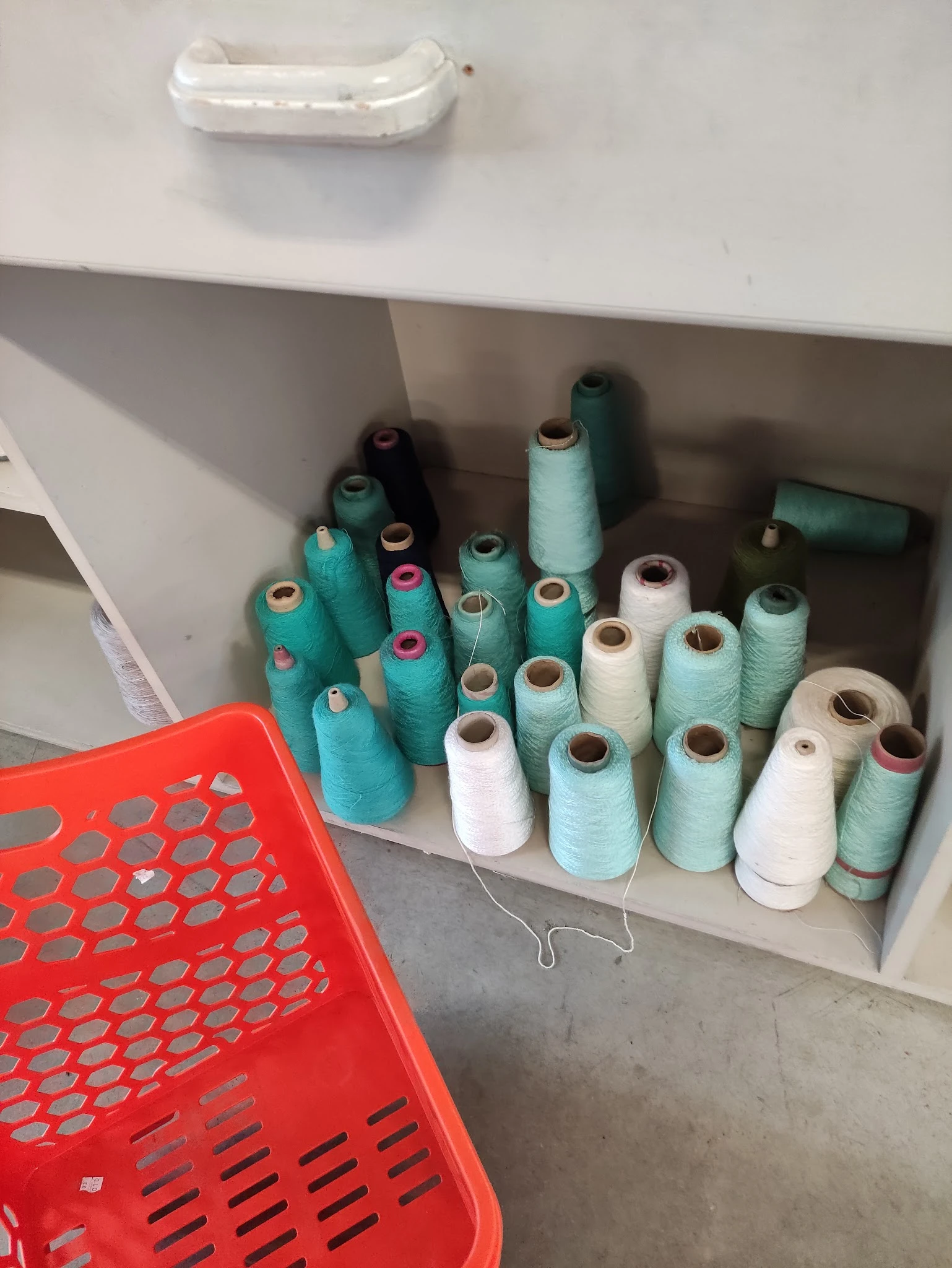 Rekken met gekleurde naaigaren in verschillende tinten turquoise, wit en beige
