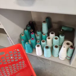 Rekken met gekleurde naaigaren in verschillende tinten turquoise, wit en beige
