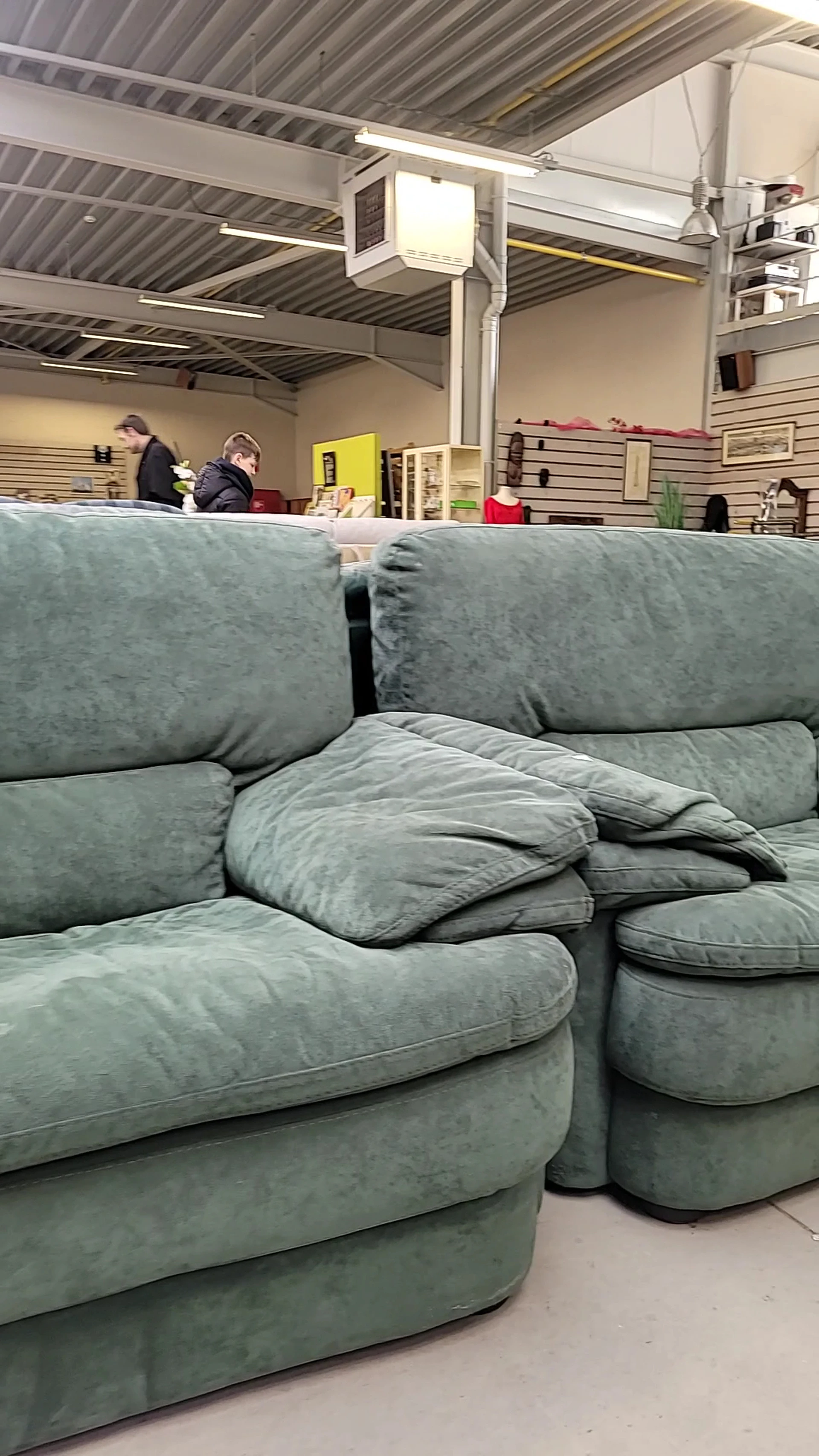 Grijze fauteuil of relaxstoel met kussens en armleuningen in tweedehands winkel