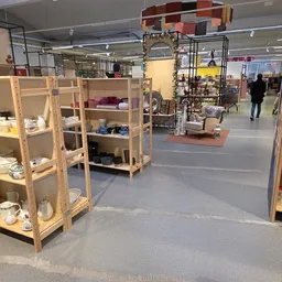 Winkelvloer met houten stellingen en vitrines vol huishoudelijke spullen in een kringloopwinkel