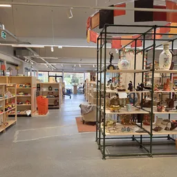 Overzicht van kringloopwinkelzaal met stellingen, vitrines en uitgestalde artikelen op meerdere niveaus