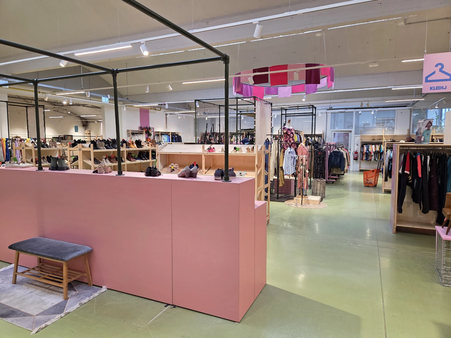 Winkelinterieur met roze winkeltheken, kledingrekken en verlichte plafonds