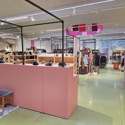 Winkelinterieur met roze winkeltheken, kledingrekken en verlichte plafonds