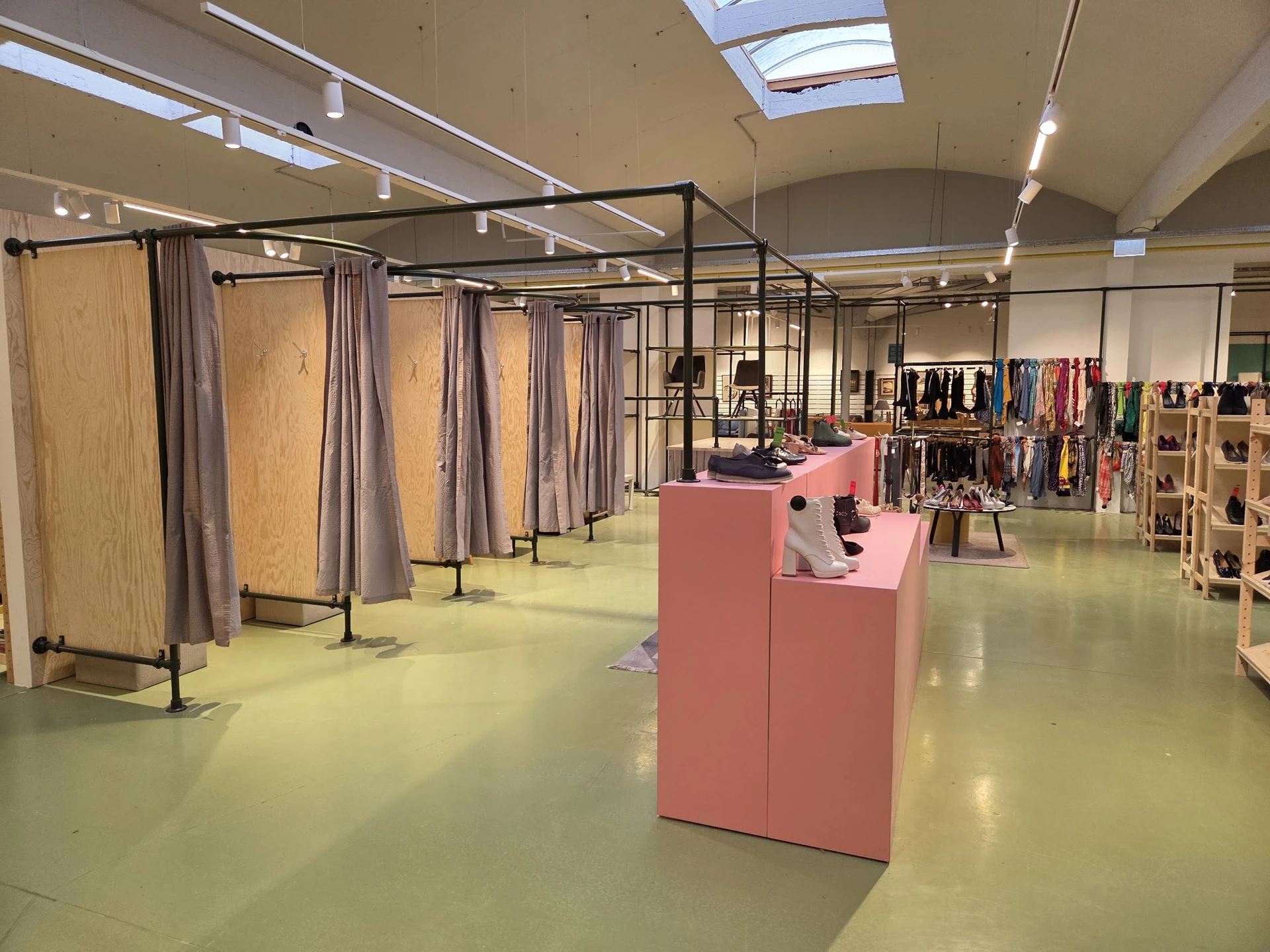 Ruime winkelruimte met paskamers, kledingrekken en displaykasten onder daglicht