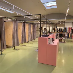 Ruime winkelruimte met paskamers, kledingrekken en displaykasten onder daglicht