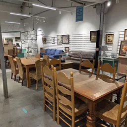 Winkelvloer met houten eettafels, stoelen, kasten en schilderijen aan de muur