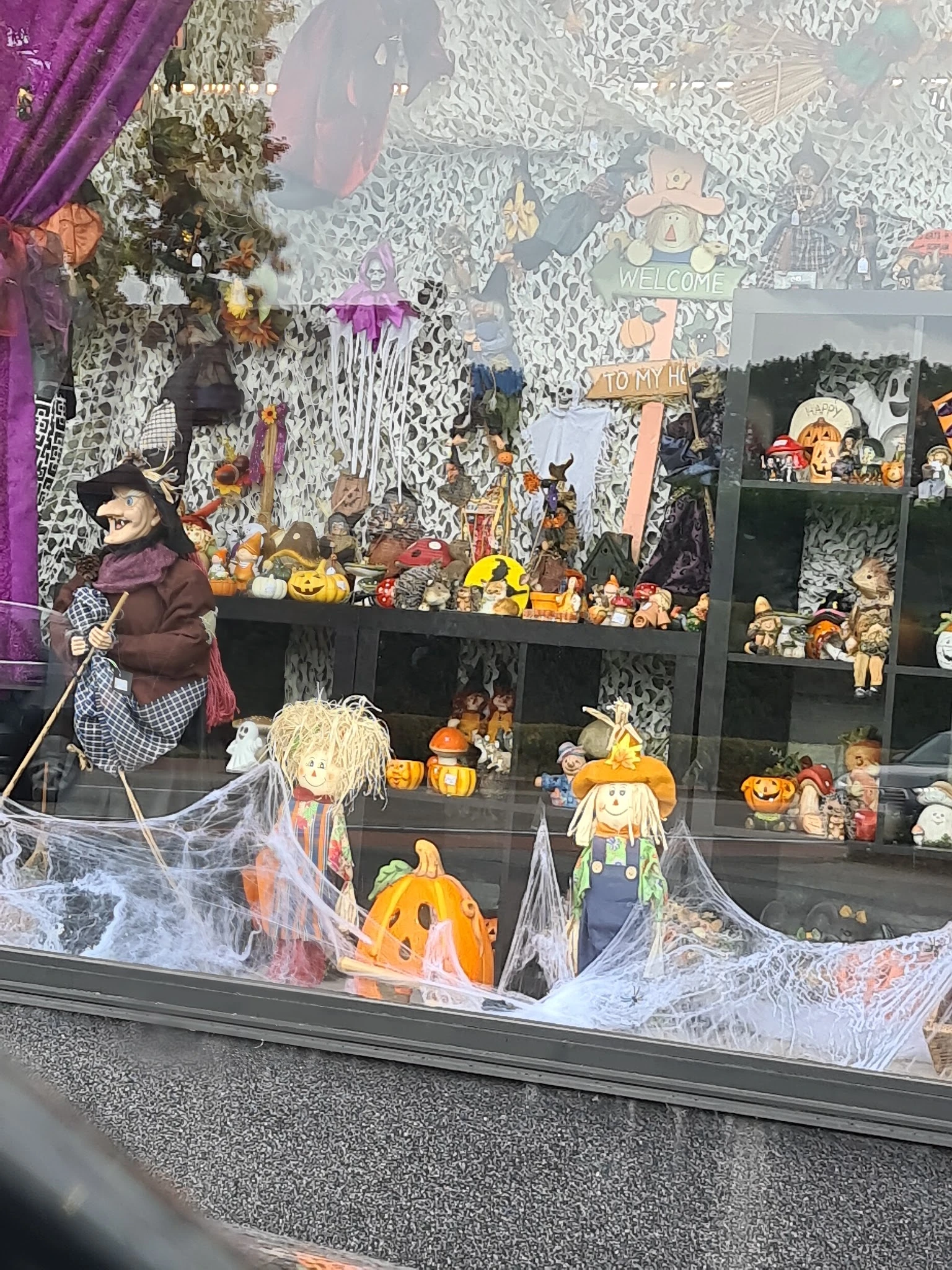 Halloweendecoratie en herfstversiering in vitrine: pompoenpoppen, skeletten, spinnenweb en diverse spookhuisfiguren