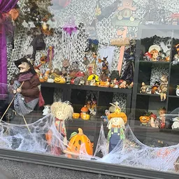 Halloweendecoratie en herfstversiering in vitrine: pompoenpoppen, skeletten, spinnenweb en diverse spookhuisfiguren