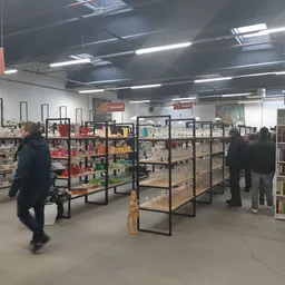 Winkelvloer met metalen stellingen gevuld met tweedehands artikelen, klanten winkelen, tl-verlichting aan plafond