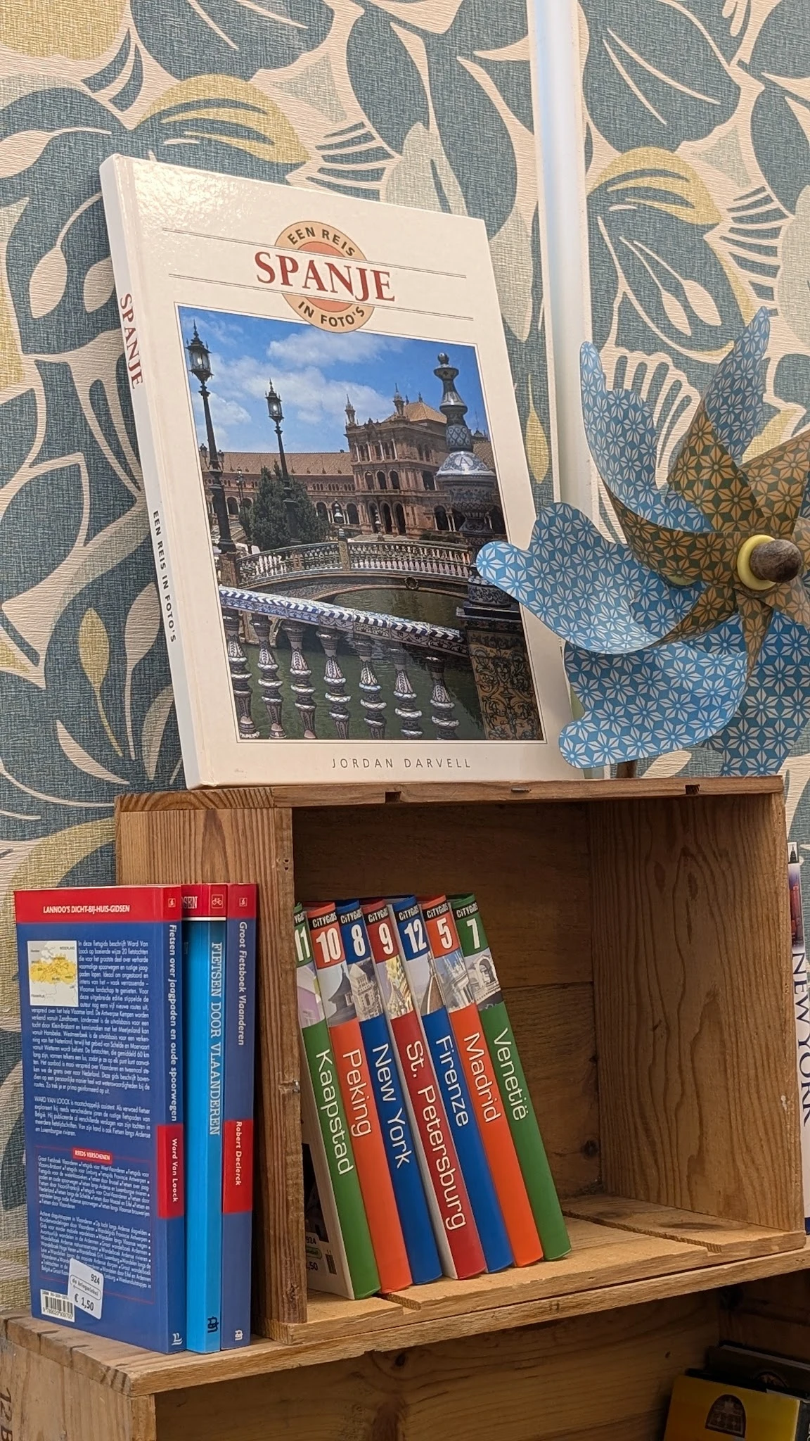 Houten kast met boeken en een fotoboek van Jordan Darvell over Sevilla op de bovenkant
