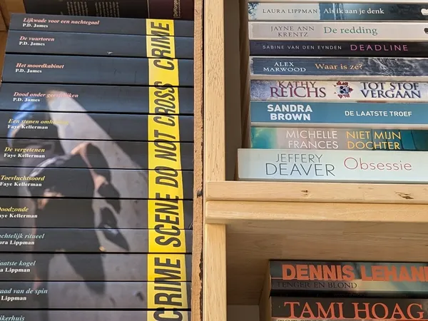 Boekenrekken met tweedehands boeken, waaronder Nederlandse titels en auteurs als P.D. James en Laura Lippman