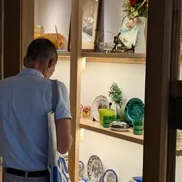 Glazen vitrinekast met diverse decoratieve items zoals groene kaarsen, plantje en serviesgoed