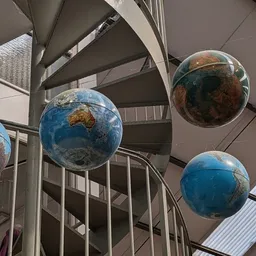 Hangende decoratieve bollen met aardkaarten in een trapopening van het winkelpand
