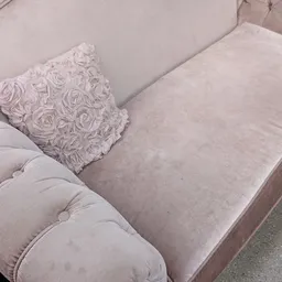 Grijze zitbank met roze gebloemd kussen, detail van meubels in kringloopwinkel