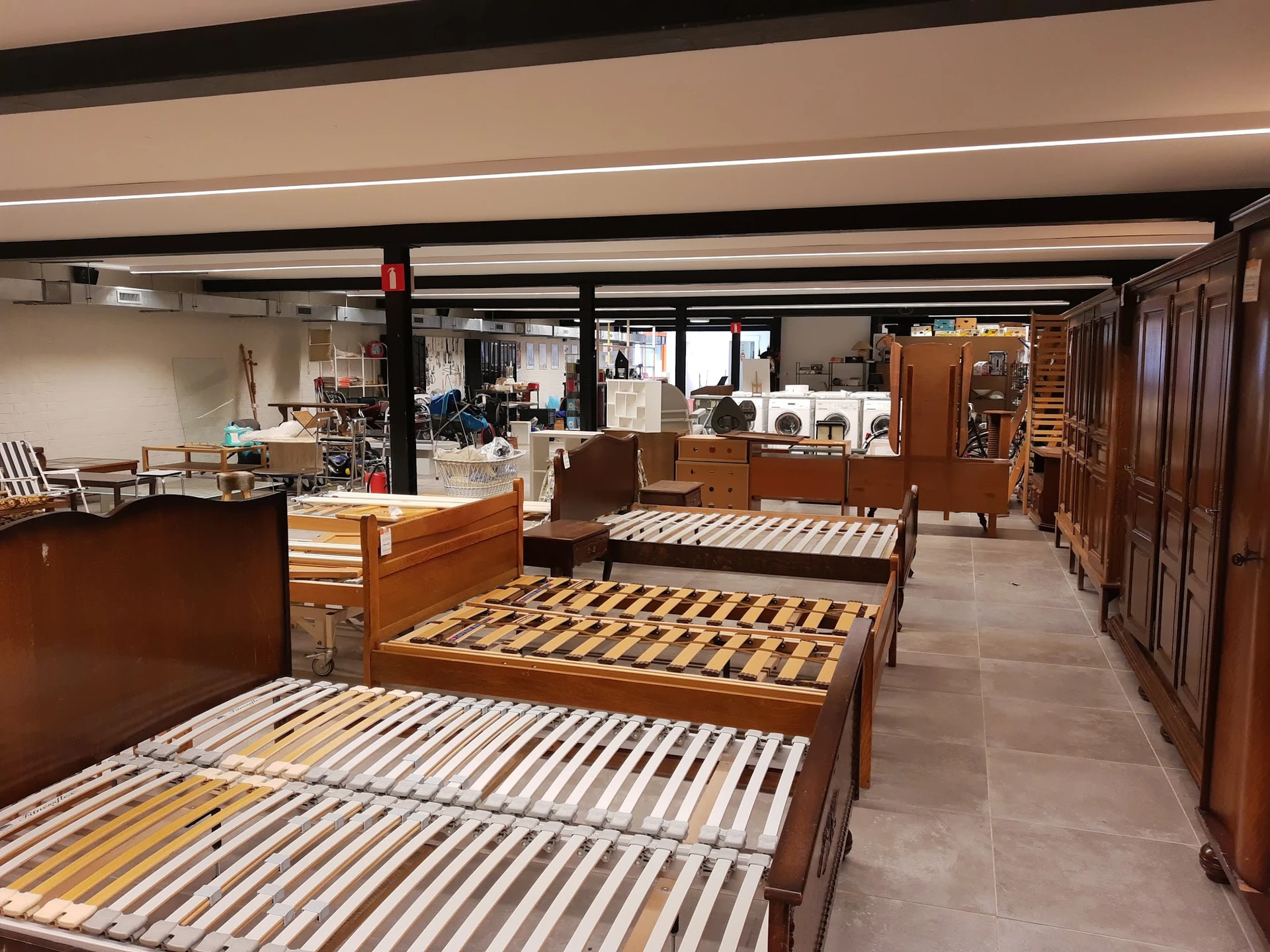 Meerdere houten bedframes met latten uitgestald in een kringloopwinkel