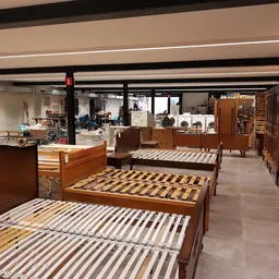 Meerdere houten bedframes met latten uitgestald in een kringloopwinkel