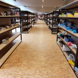 Winkelinterieur met donkere metalen stellingen langs beide zijden vol met boeken, decoraties en huishoudartikelen