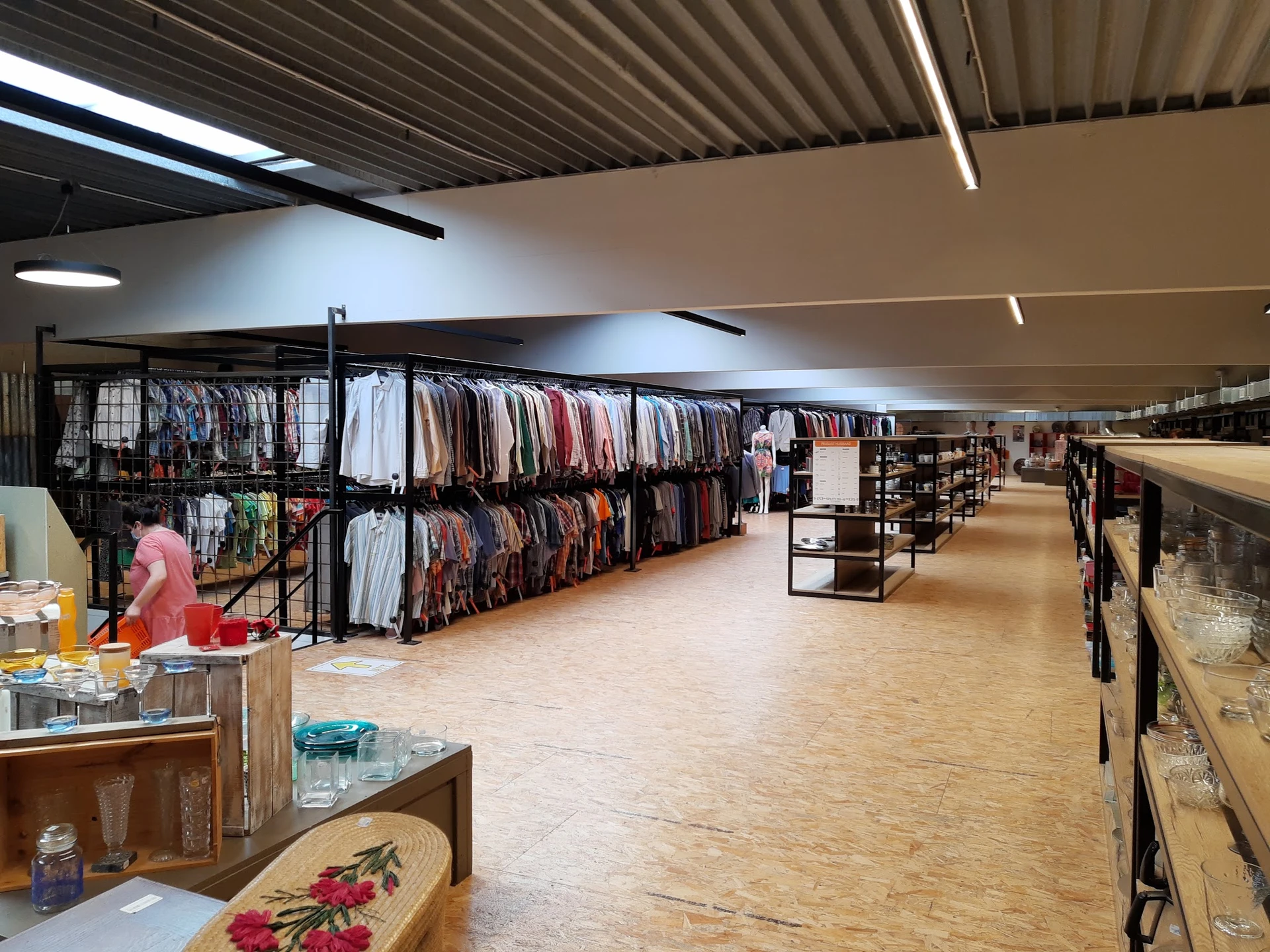 Winkelvloer van kringloopwinkel met rekken vol kleding, stellingen en toonbank